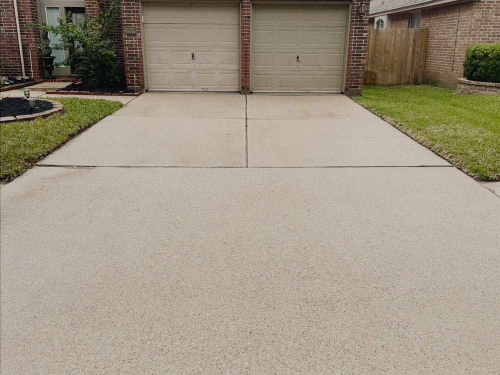 A clean two-story brick home with a freshly washed driveway.